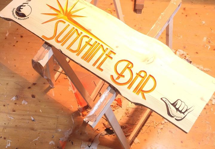 Großes Holz-Firmenschild vor Garagentor